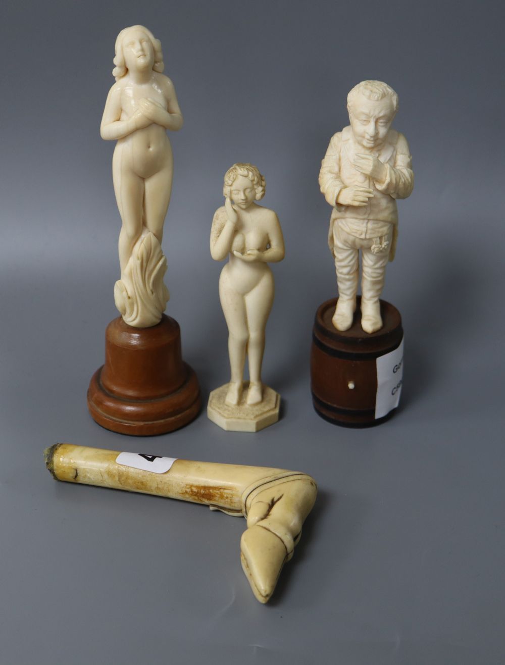 Three carved ivory figures and a parasol handle carved as a hoof, tallest 16.5cm